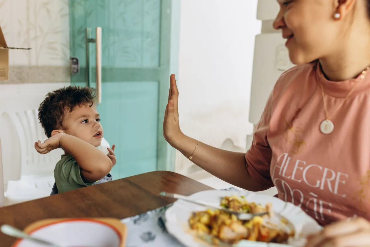 Mama sandalyesindeki küçük çocuk ve annesi sofrada çak beşlik yapıyor